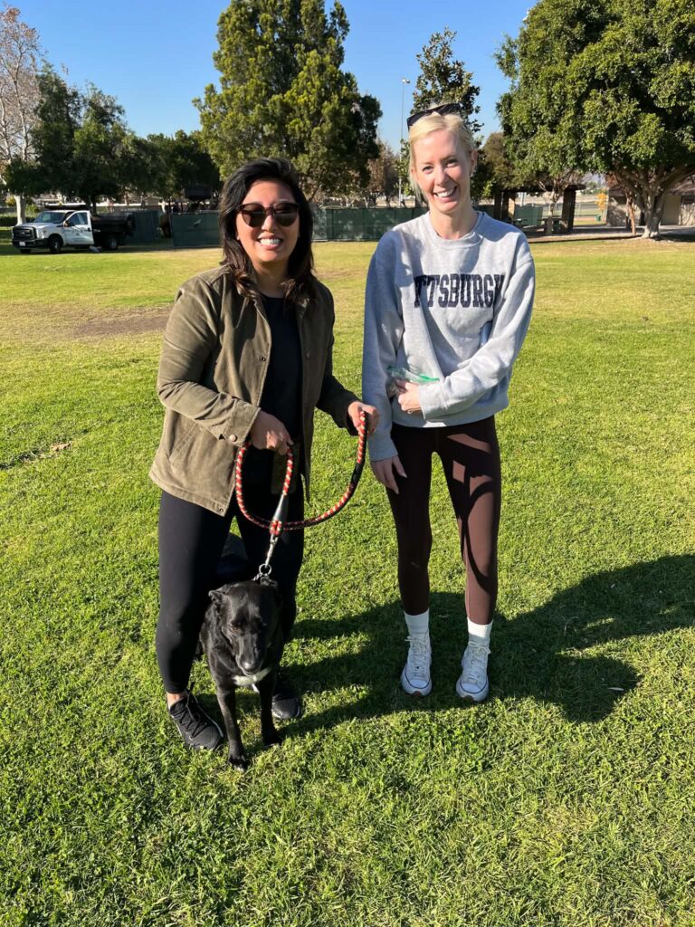 Isabella standing on a grassy field with two smiling women during her adoption.