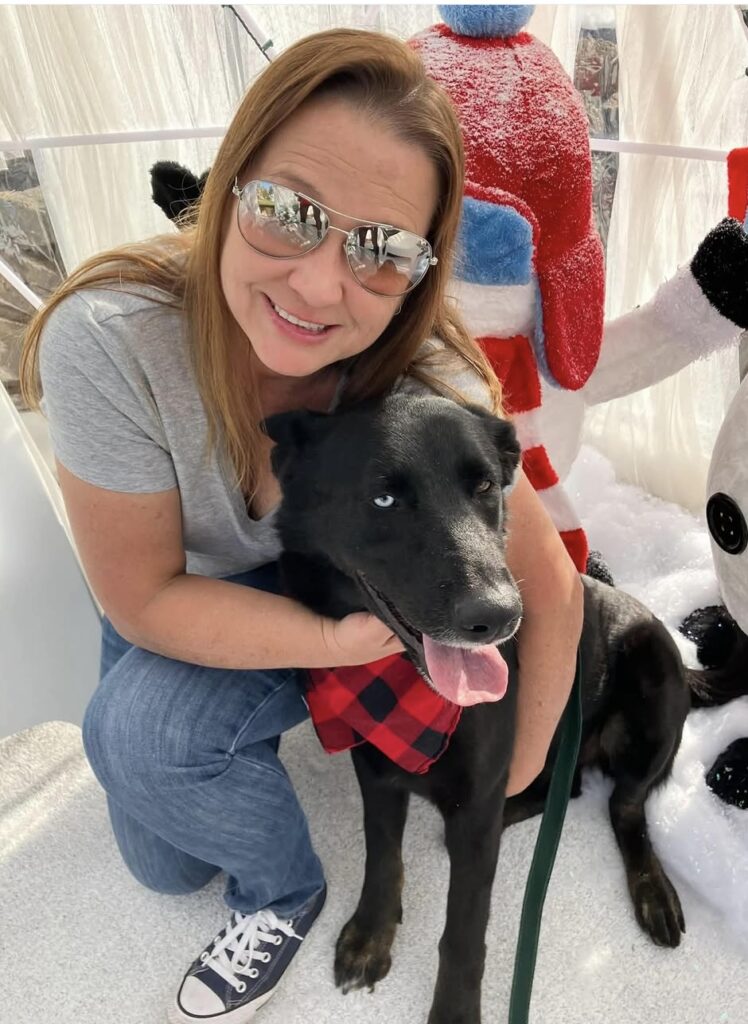 Labradors and Friends volunteer Lina hugging Kira at a holiday event.