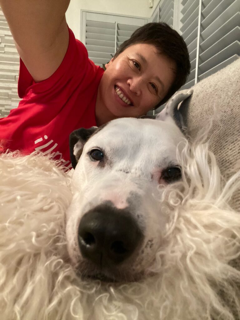 Dottie cuddling on a couch with a Brooke, her face resting comfortably on a soft blanket.